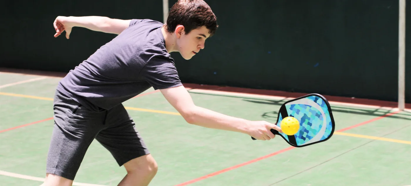 Kids playing pickleball mid-skill